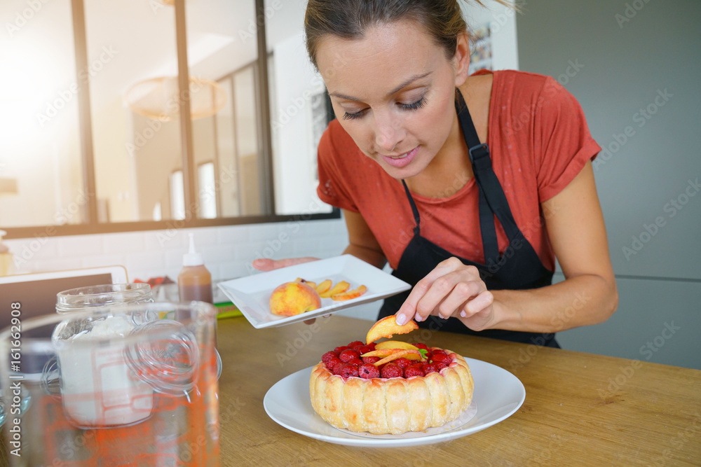 Young woman in modern kitchen baking raspberry cake