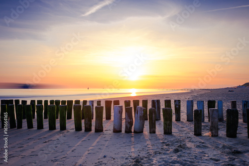 Sonnenuntergang in Zeeland am Strand mit Holzpfählen im Sand