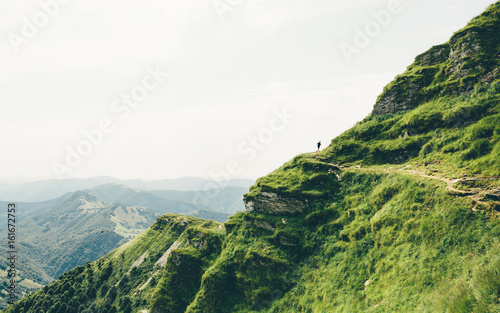 Distant trail runner in epic mountain landscape