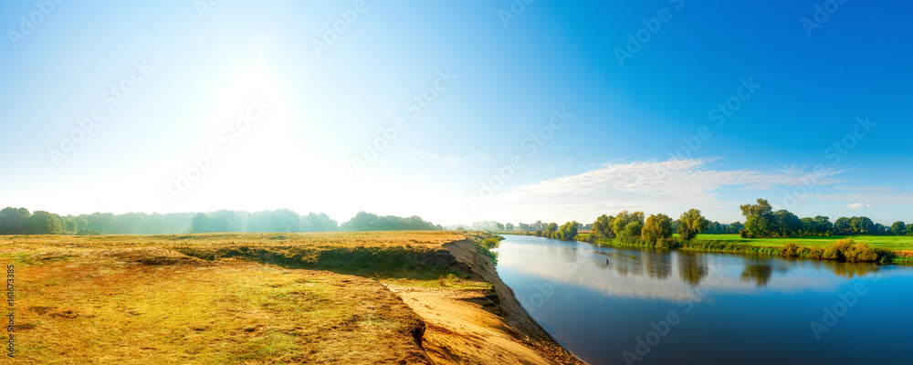Obraz premium Idyllische Landschaft mit Fluss, Wiesen und Bäumen