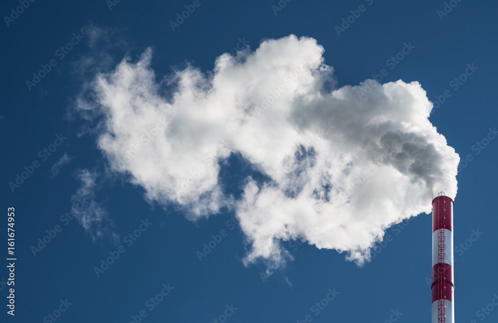 Dirty smoke from red and white smokestack on blue sky Dirty smoke from red and white smokestack on blue sky