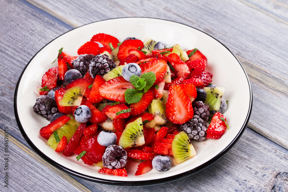 Strawberry, blackberry, blueberry and kiwi salad, garnished with mint. Fruit and berry salad