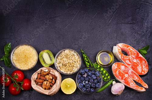 Selection of healthy and good for heart food. Healthy food concept with salmon, fresh vegetables, fruits and ingredients for cooking on dark background. Top view with copy space