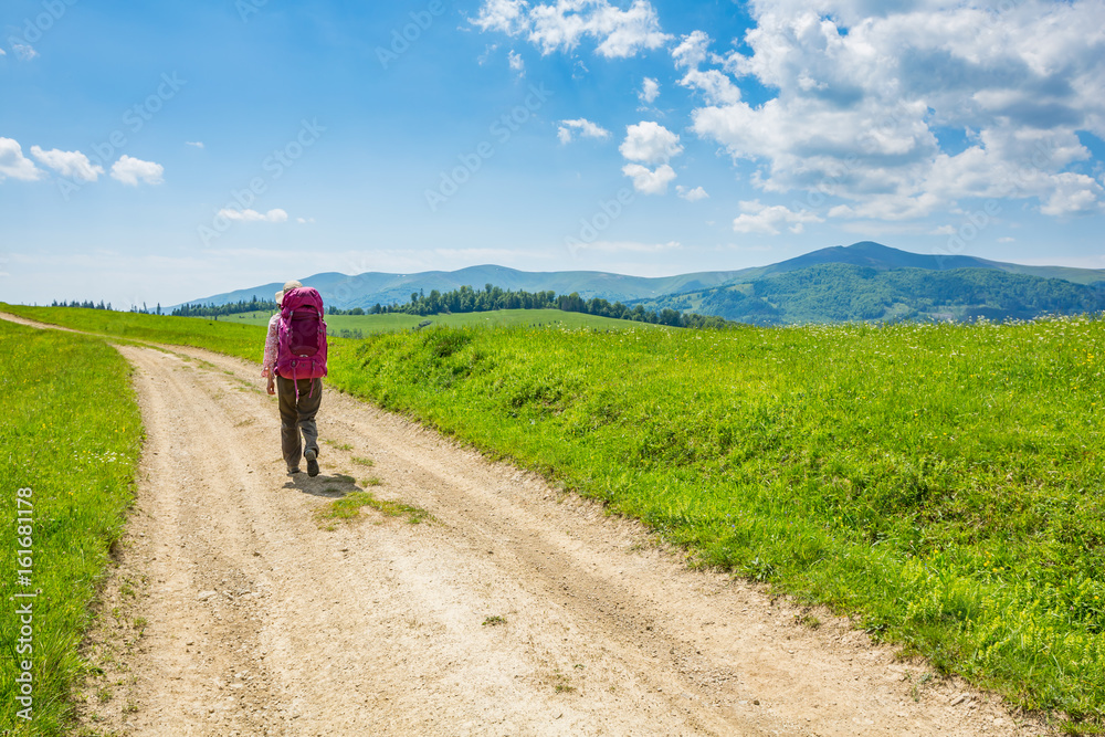 A woman with backpack and road.