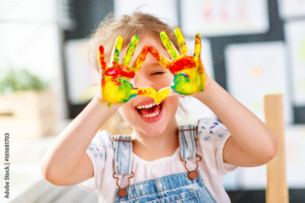 funny child girl draws laughing shows hands dirty with paint - obrazy, fototapety, plakaty 