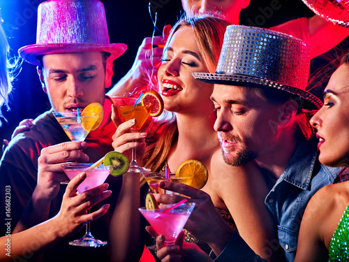 Klub nocny disco kobieta. Impreza taneczna z grupą ludzi tańczących Kobiety i mężczyźni bawią się i piją koktajl martini z owocami w nocnym klubie. Picie alkoholu owocowego na prywatnej imprezie.
