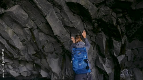 Woman exploring cave on Reynisfjara beach near Vik, Icealnd