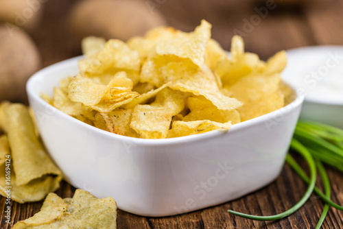 Portion of Potato Chips with Sour Cream taste on wooden background (selective focus)