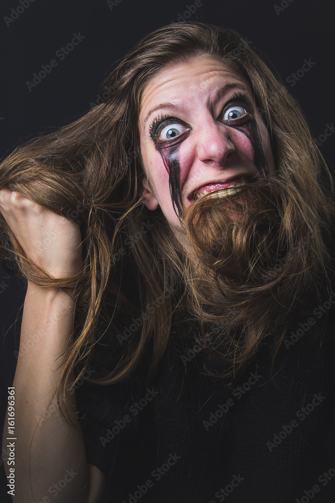 Crazy deranged woman pulling her hair out, scary and insane, halloween concept, possessed by evil spirits