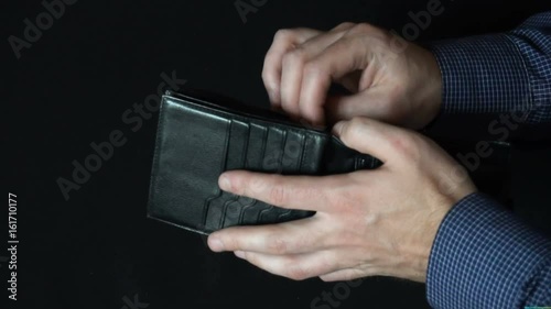 Taking Money Out of a wallet. The man opens a leather wallet and pulls out a 100 dollar bills. slow motion photo