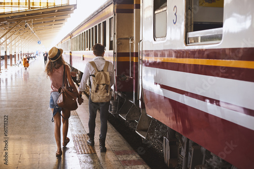 Two persone guy and girl travellers waiting for a train in asian train station