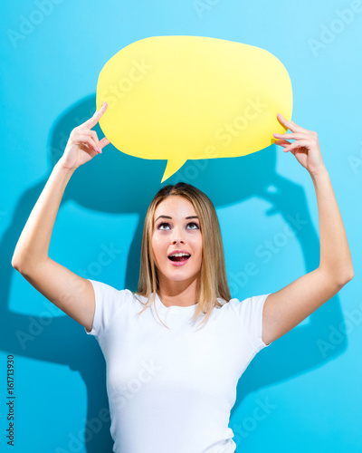 Young woman holding a speech bubble on a blue background