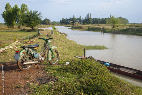 Classic bike and boat in countryside.