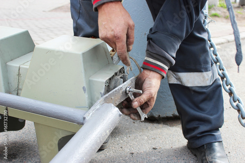 The worker replaces the broken traffic light with a working traffic light. Unscrewing parts with lamps from fastening with a spanner.