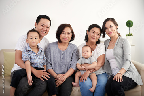 Portrait of big Asian family posing for photo at home, all smiling happily looking at camera