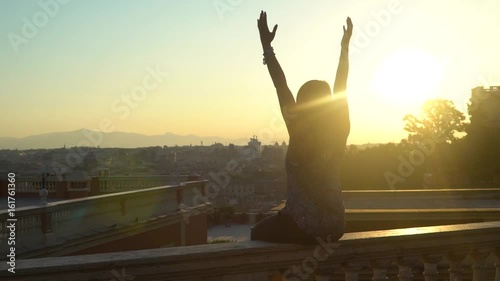 Woman raising hands in air at sunrise overlooking Rome, Italy
