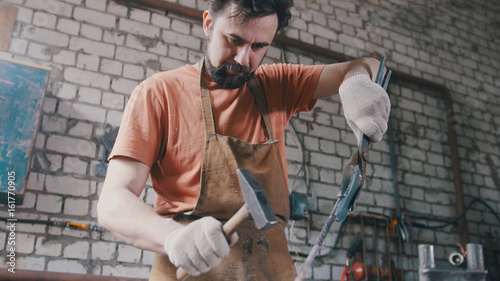 Blacksmith with hammer in forge creating steel knife