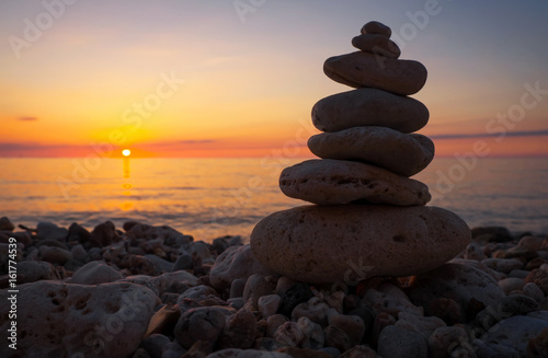 Pyramid of the small pebbles on the beach. Stones, against the background of the sea shore during sunset