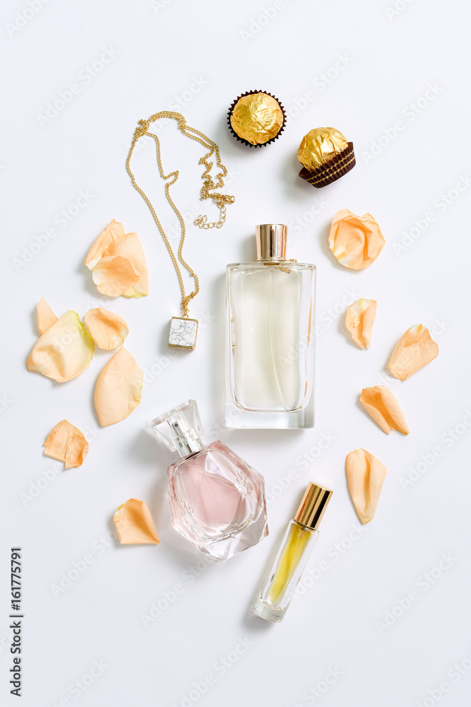 Perfume bottles with flowers petals on white background. Perfumery, cosmetics, jewelry and fragrance collection. Stylized feminine flatlay. Women accessories top view.