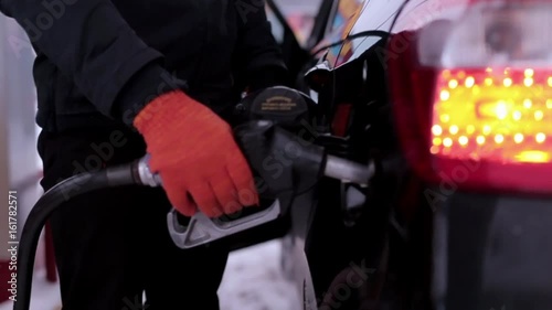 Man pours gasoline into a car at a gas station