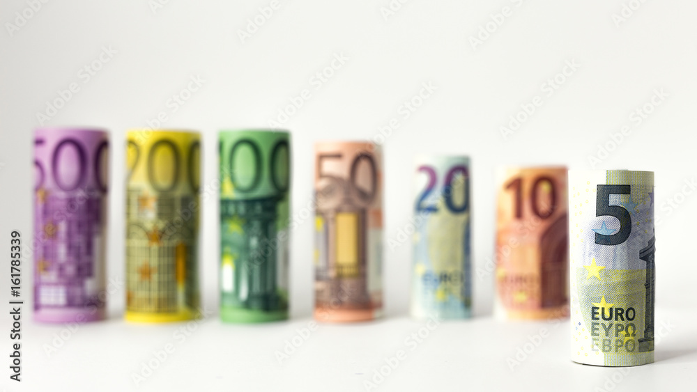 Gerollter 5 Euro Schein mit anderen Geldscheinen im Hintergrund Gerollter 5 Euro Schein mit anderen Geldscheinen im Hintergrund