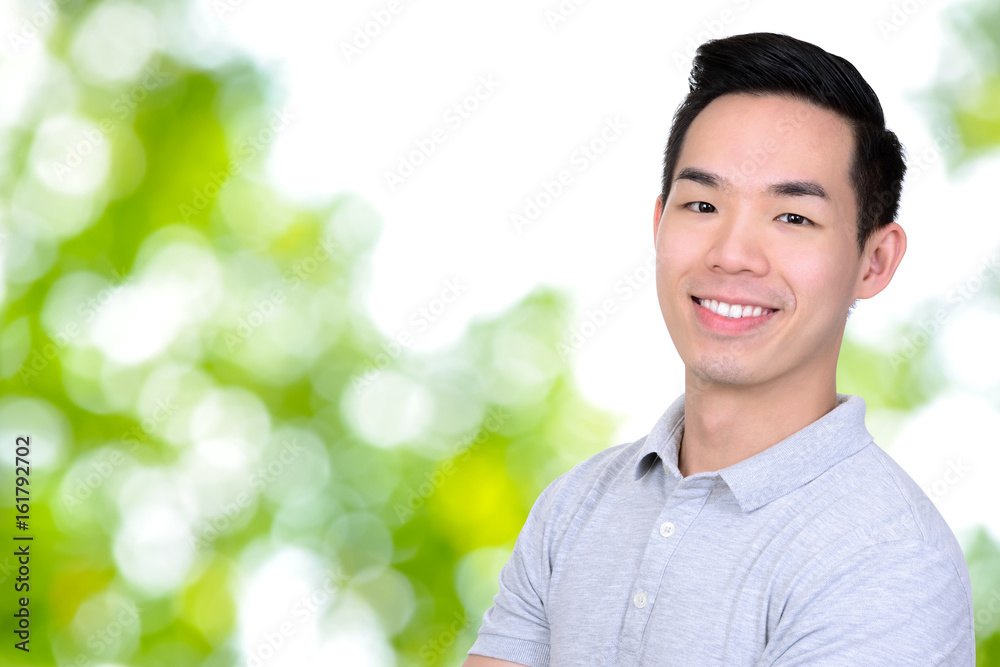 Happy smiling young Asian man on bokeh green abstract background