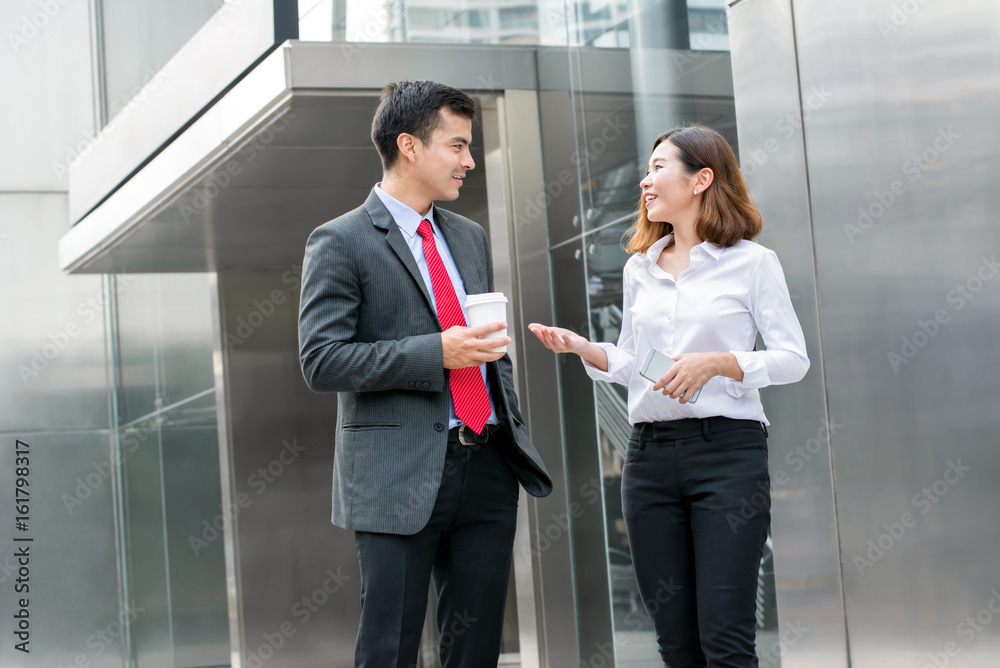 Business colleagues talking while walking in front of office building Business colleagues talking while walking in front of office building