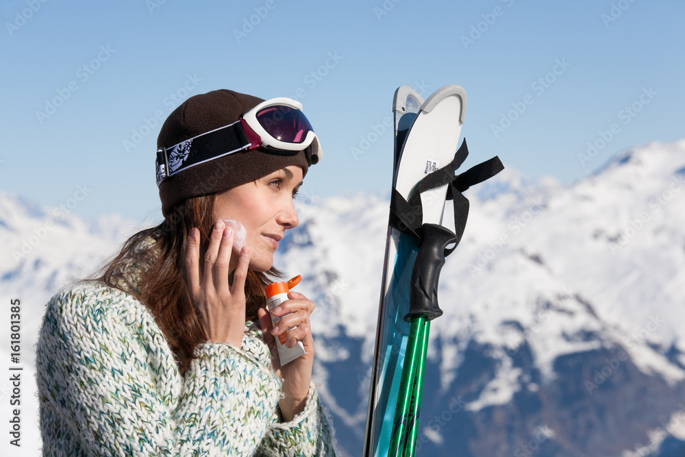 femme à la neige qui met de la crème solaire sur son visage Photos | Adobe  Stock