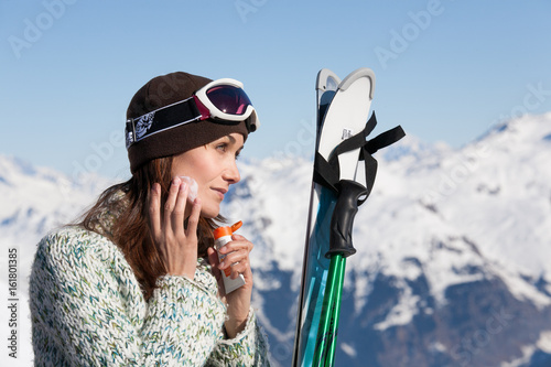 femme à la neige qui met de la crème  solaire sur son visage