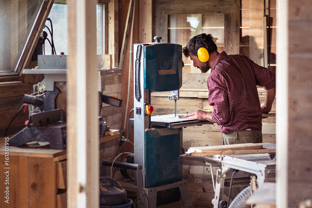 Male Carpenter cutting plank by band saw Male Carpenter cutting plank by band saw