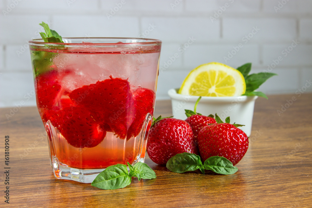 A refreshing summer drink with ice, strawberries and lemon on a wooden background. The concept of fruit drink. A refreshing summer drink with ice, strawberries and lemon on a wooden background. The concept of fruit drink.