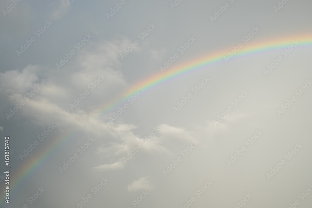 A Colorful Rainbow after rain with fluffy gray cloudy sky, full color spectrum.
