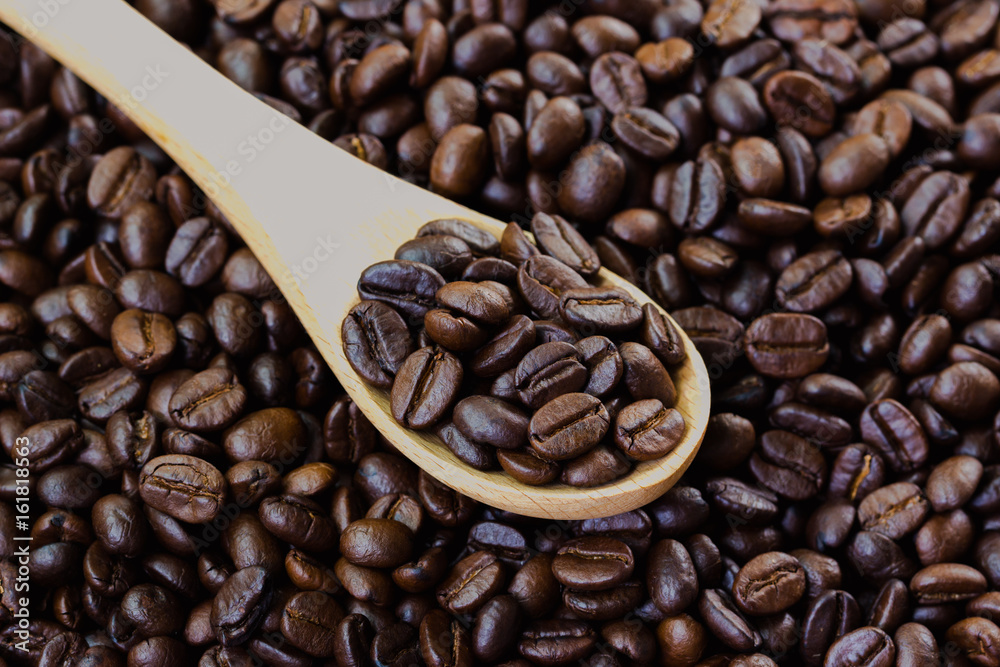Coffee beans in wood spoon on stack of coffee beans. Close up of coffee beans concept for background and wallpaper. Macro concept for background and texture. Coffee beans in wood spoon on stack of coffee beans. Close up of coffee beans concept for background and wallpaper. Macro concept for background and texture.