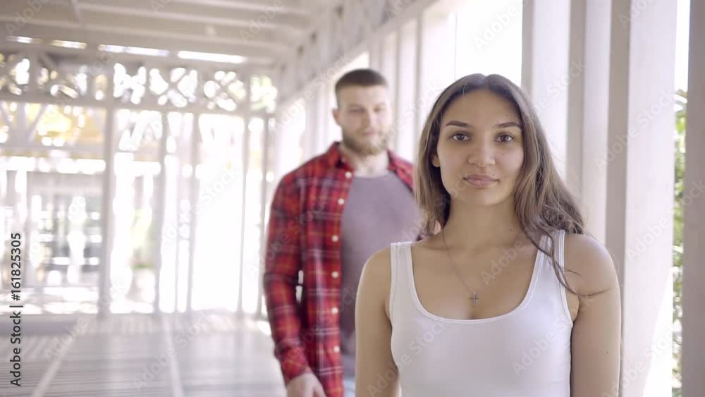 Eastern young pretty girl in a white tank top . Back moving closer to the European athletic big man with a beard and takes her hands over naked shoulders. Eastern young pretty girl in a white tank top . Back moving closer to the European athletic big man with a beard and takes her hands over naked shoulders.