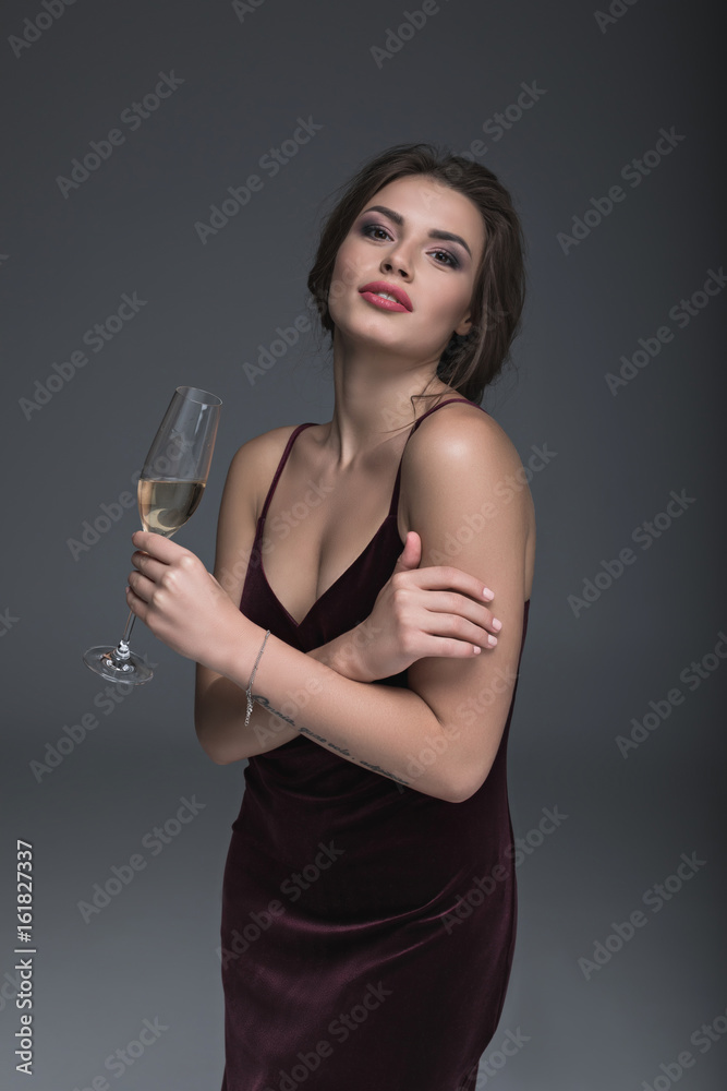 young lady in evening dress holding glass of champagne and looking at camera young lady in evening dress holding glass of champagne and looking at camera