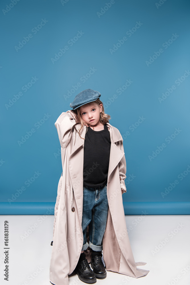 Full length view of adorable little girl in cap posing in studio and looking at camera Full length view of adorable little girl in cap posing in studio and looking at camera
