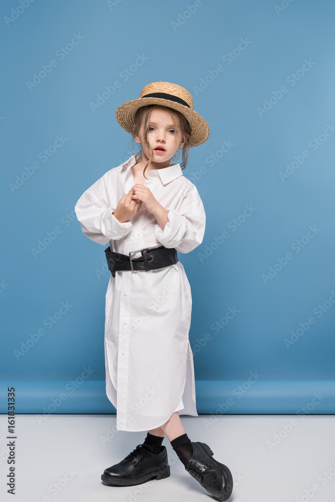 stylish little girl posing in white shirt and straw boater, studio shot on blue stylish little girl posing in white shirt and straw boater, studio shot on blue