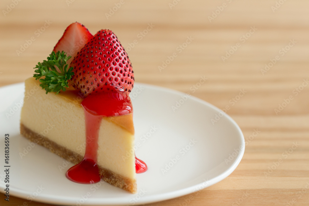 Homemade New York cheesecake on white plate decorated by strawberry,parsley and strawberry sauce. Moist and smooth classic baked cheesecake. Copy space background of delicious New York cheesecake. Homemade New York cheesecake on white plate decorated by strawberry,parsley and strawberry sauce. Moist and smooth classic baked cheesecake. Copy space background of delicious New York cheesecake.