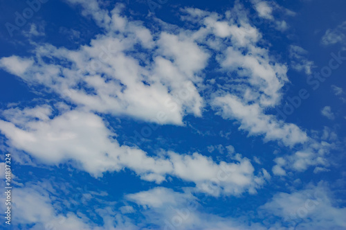 Beautiful deep blue sky with white diagonally clouds at sunny day. Abstract natural background with thick fluffy clouds