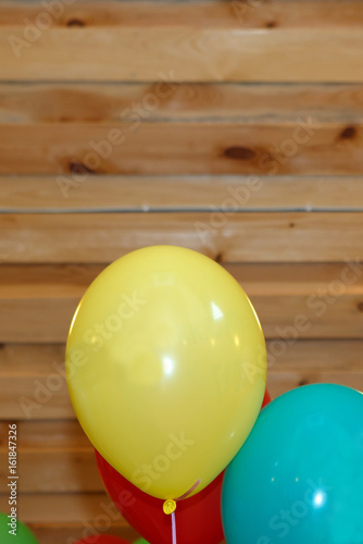 Balloons on a wooden background. Festive multicolored gel balloons in the air.