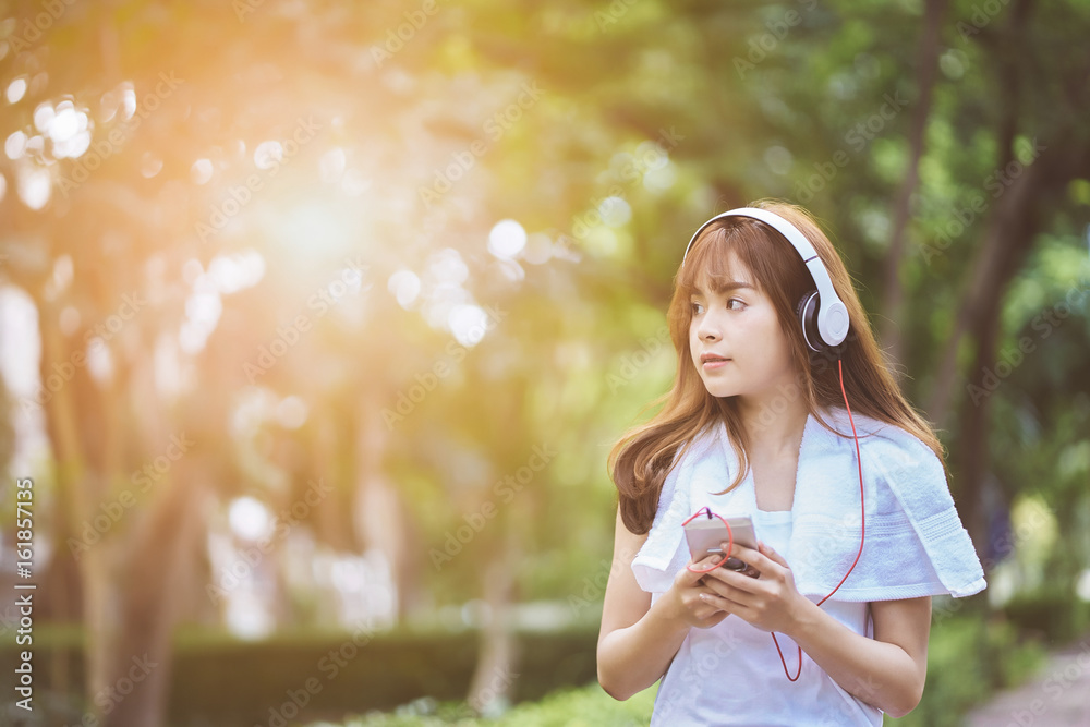 Women with headphones jogging and relaxing stroll in the park happy. Women with headphones jogging and relaxing stroll in the park happy.