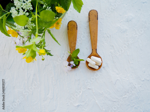 Alternative health fresh plants and herbal capsules in wooden spoon on white background, space for text, alternative medicine, vegetarianism, natural medicine photo