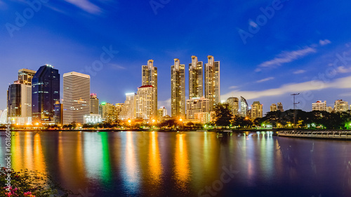 Bangkok city skyline and office buildings in twilight time with skyscrapers and lights reflecting in the lake at Benjakitti Public Park  Bangkok  Thailand.