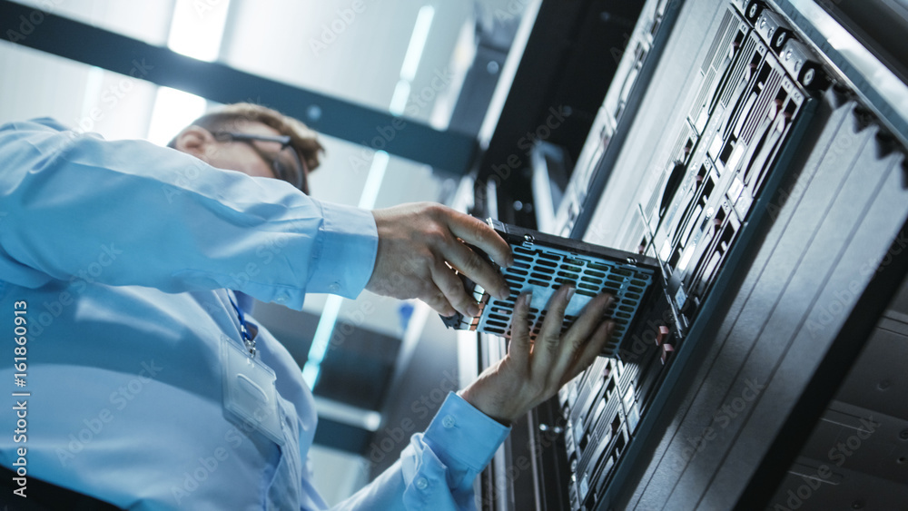 Long Angle Shot In Fully Working Data Center of IT Engineer Installing Hard Drive into Server Rack. Detailed and Technically Accurate Footage. Long Angle Shot In Fully Working Data Center of IT Engineer Installing Hard Drive into Server Rack. Detailed and Technically Accurate Footage.