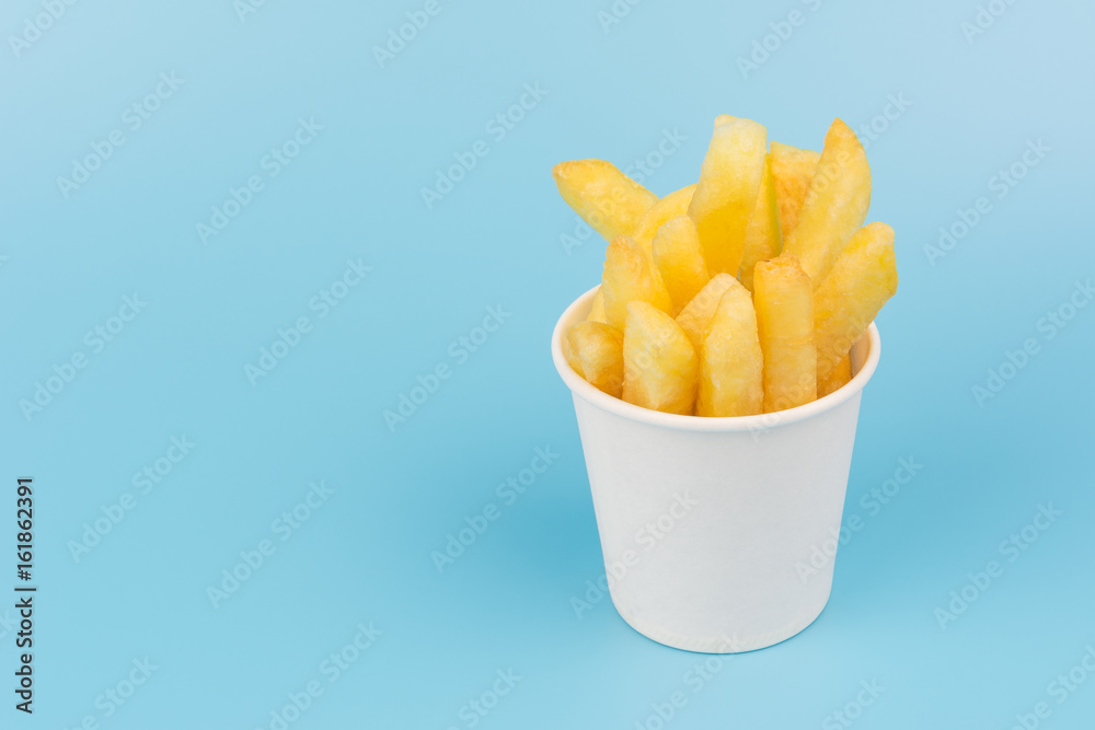 french fries in a paper cup on blue background french fries in a paper cup on blue background