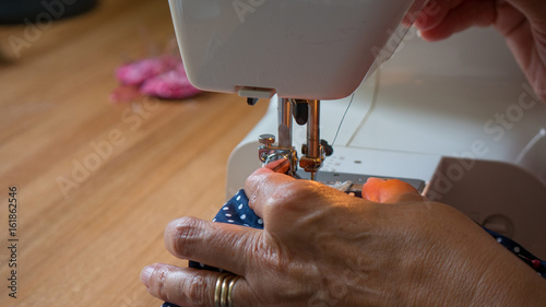 female hand using sewing machine stitching fabic in studio