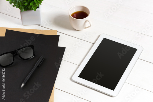 Modern workplace with digital tablet computer and mobile phone, cup of coffee, pen and empty sheet of paper.