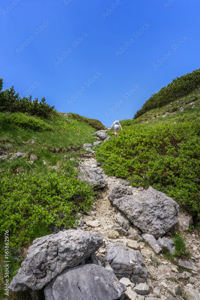 Frau läuft steinigen Wanderweg hinauf