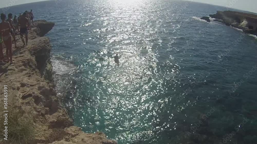 tourist jumping from cliff in the sea at sea caves, Cyprus 