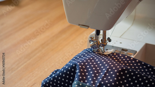 female hand using sewing machine stitching fabic in studio